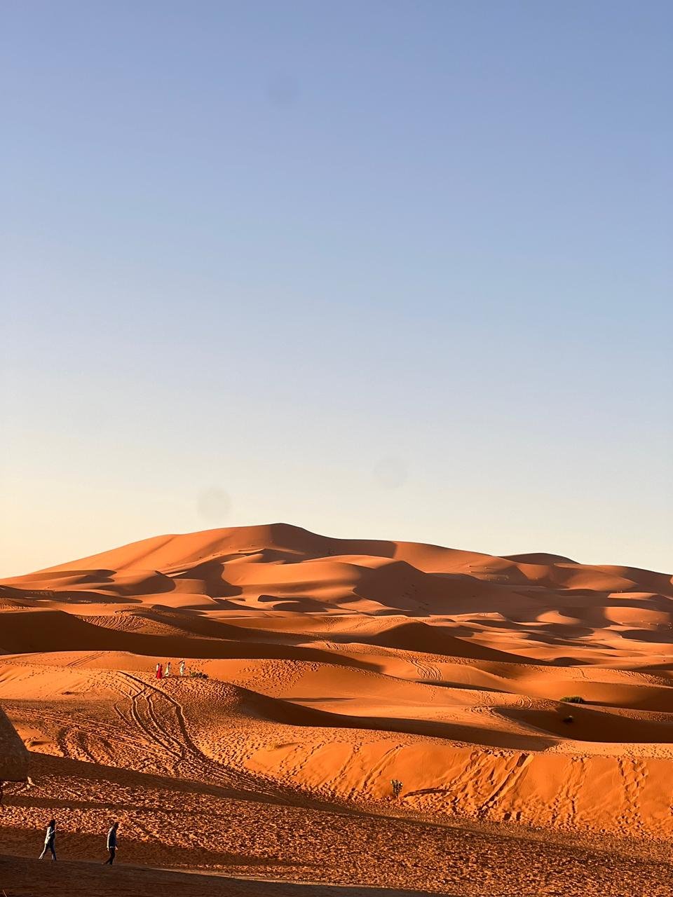 Erg Chebbi dunes near Merzouga at golden hour, with footprints across the sand.